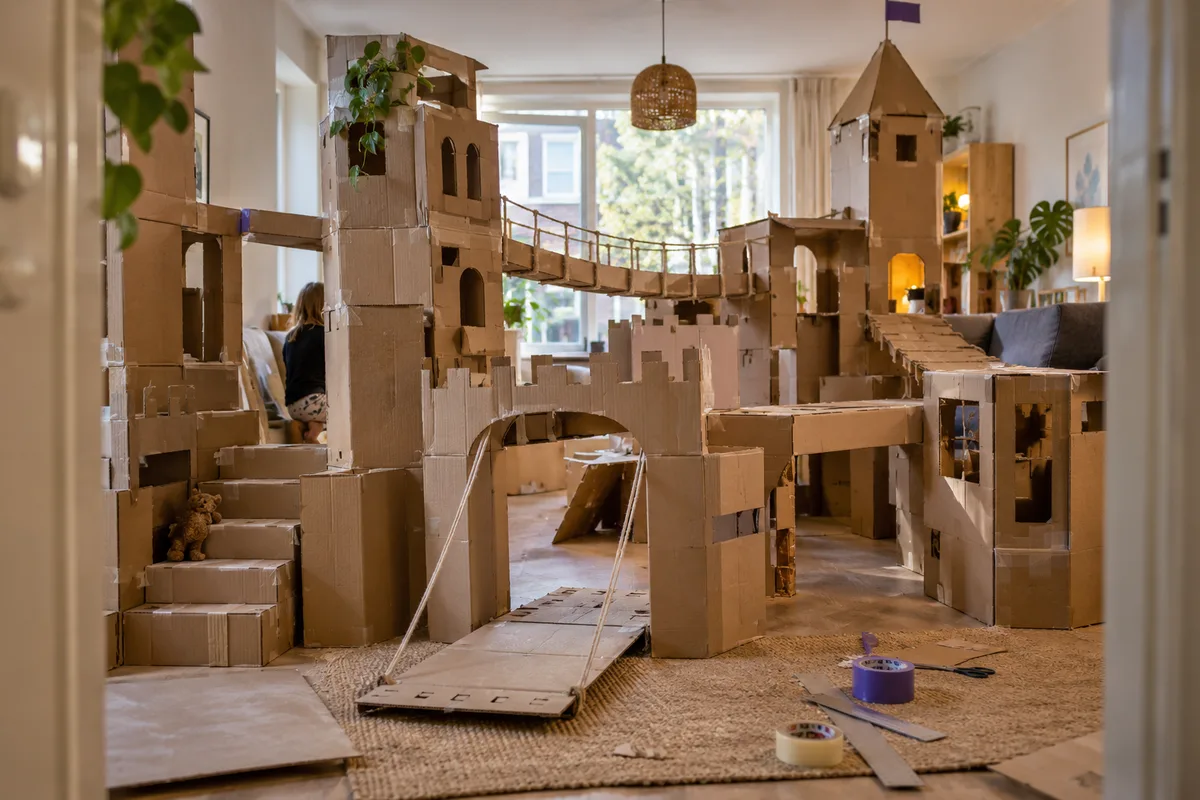 Kinderen bouwen een hut, toren en auto van lege kartonnen dozen